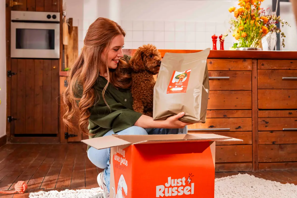 Woman with a poodle dog unboxing a Just Russel delivery